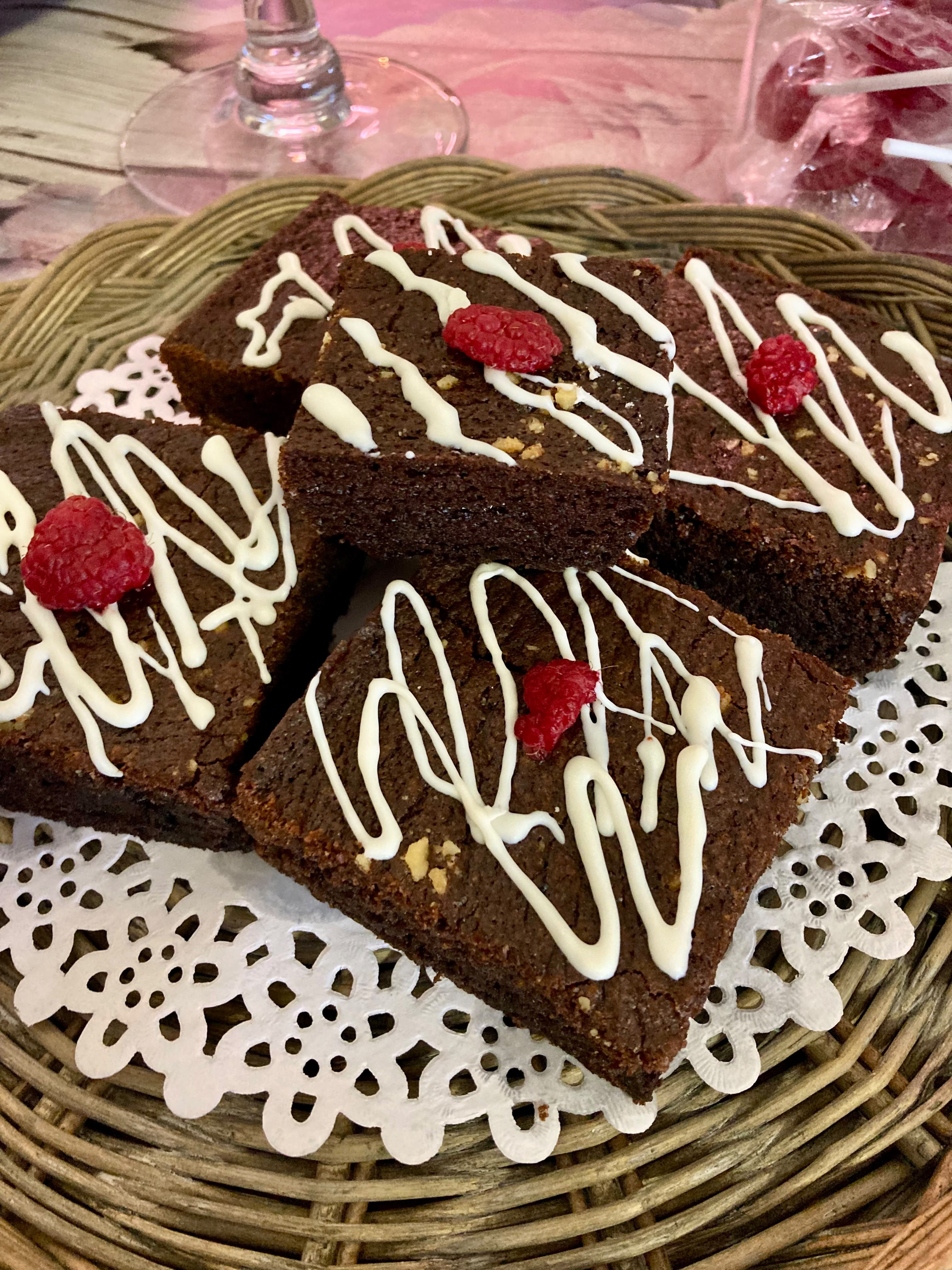 Sjokoladebrownies in wiggies gesny, met witsjokoladestrepe and vars framboese bo-op, op 'n kantpapier